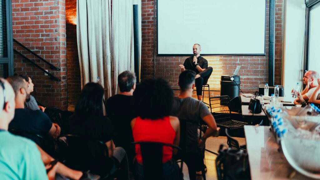 pexels-photo-3321791-3321791 A dynamic seminar with a speaker engaging a diverse audience in a modern indoor setting.