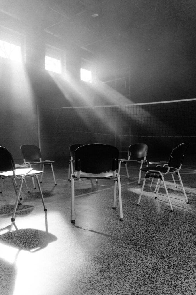 pexels-photo-5710924-5710924 Black and white photo of an empty hall with chairs in a circle, sunrays penetrating through windows.